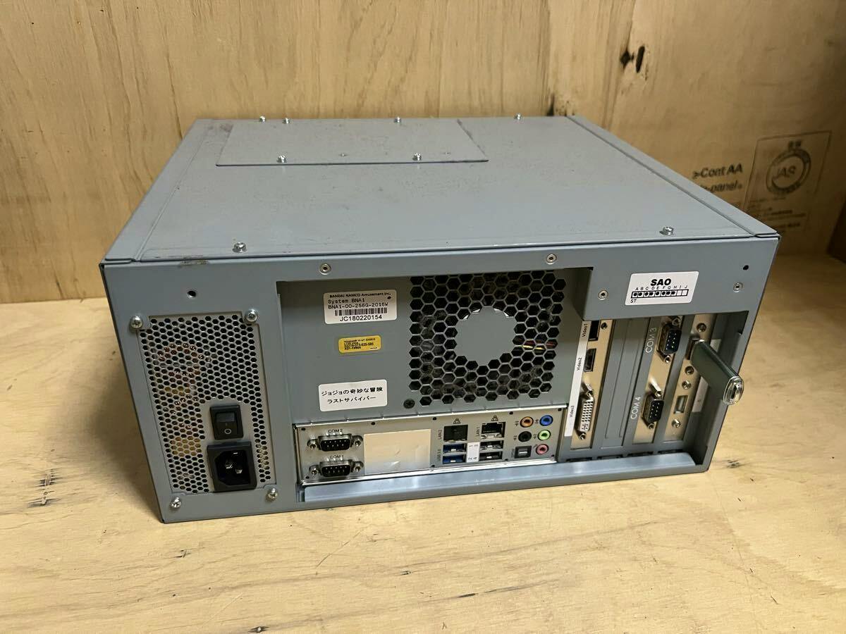 Rear view of the BANDAI NAMCO arcade PCB chassis showing power inlet, cooling fan, serial ports, audio/video ports, expansion slots, and labels.