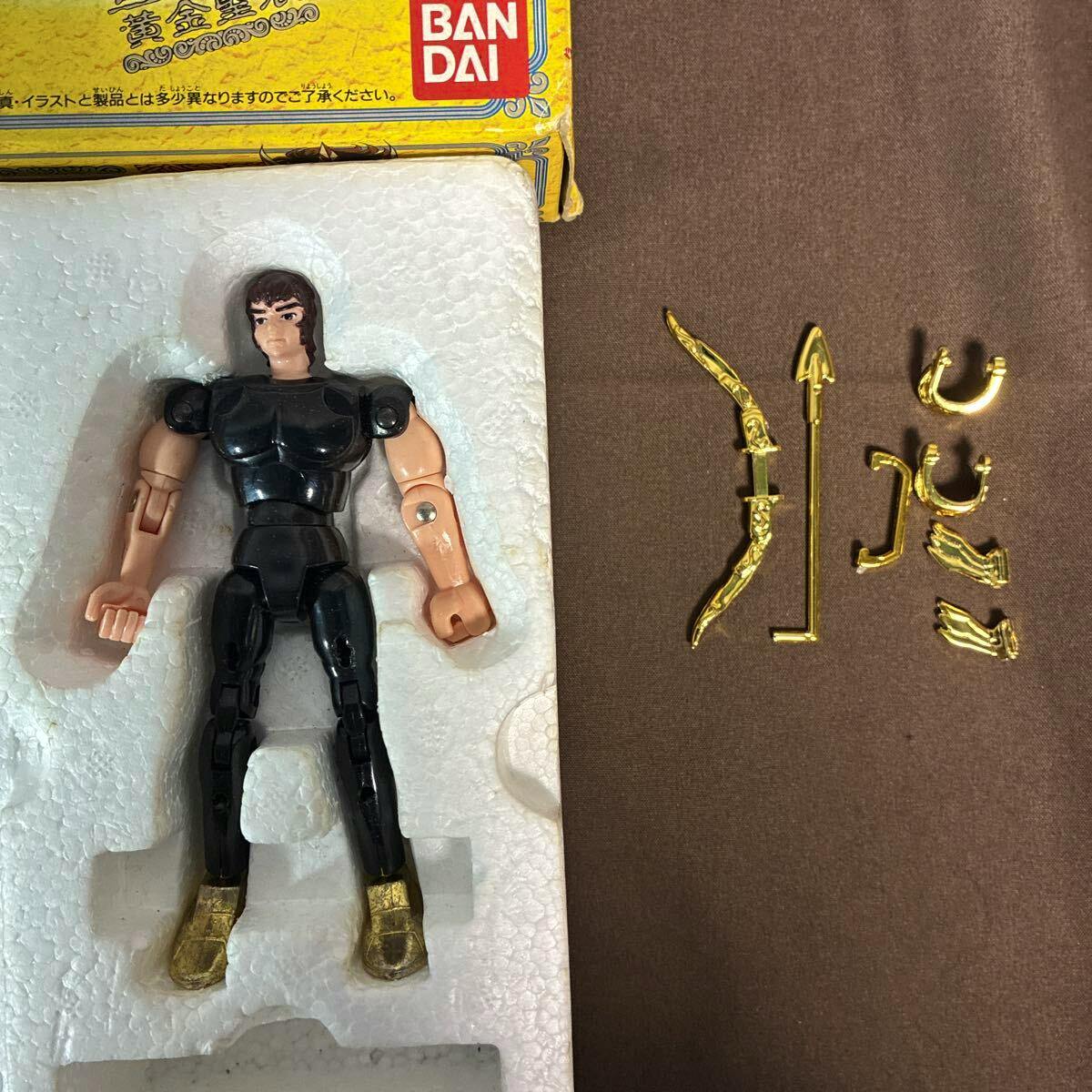 Saint Seiya Sagittarius plastic action figure seated in a foam tray with separate gold-colored armor pieces arranged to its right.