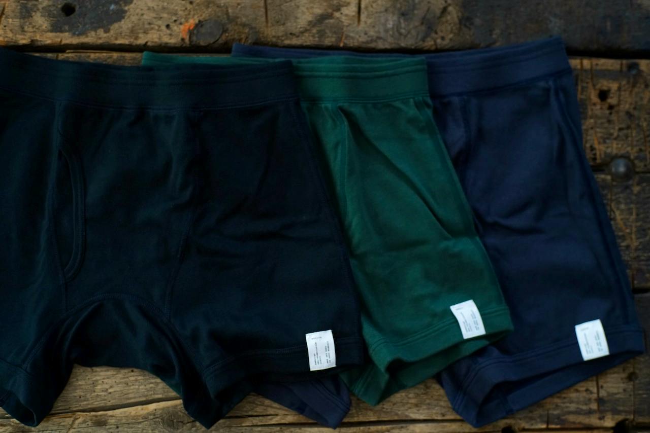 Three BARAILLE&GARMENTS ISLAY boxer briefs in dark tones laid flat on a wooden surface.