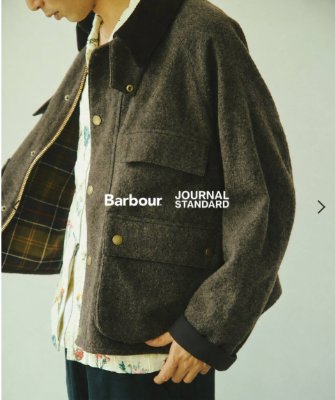 A model wearing the cropped wool men's jacket with visible tartan lining and front flap pockets.