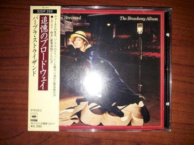 Front of a CD jewel case for Barbra Streisand's The Broadway Album showing the album cover and a Japanese obi strip on a wooden surface.