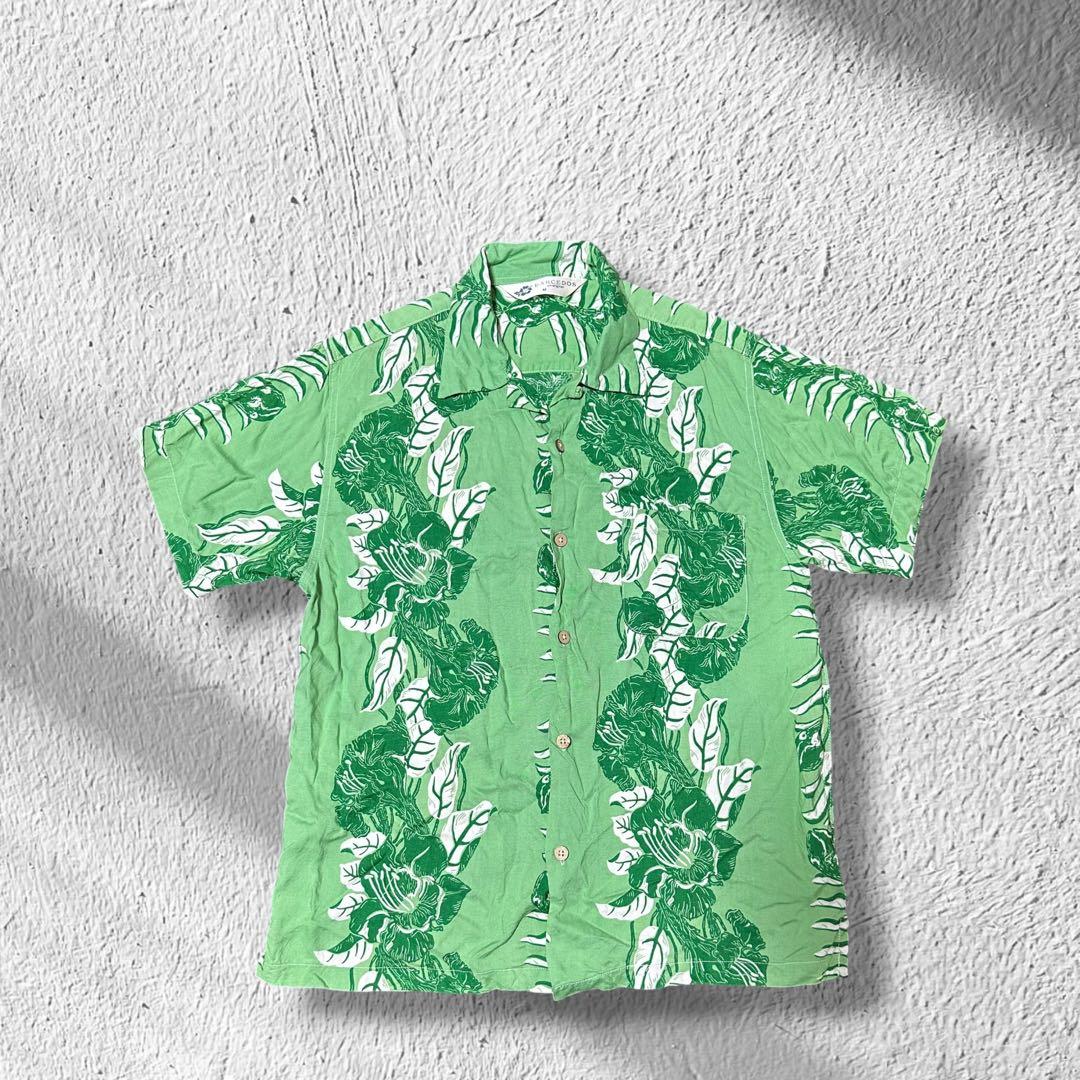 Green rayon men's Aloha (opening-collar) shirt with white floral print laid flat showing the front and collar.