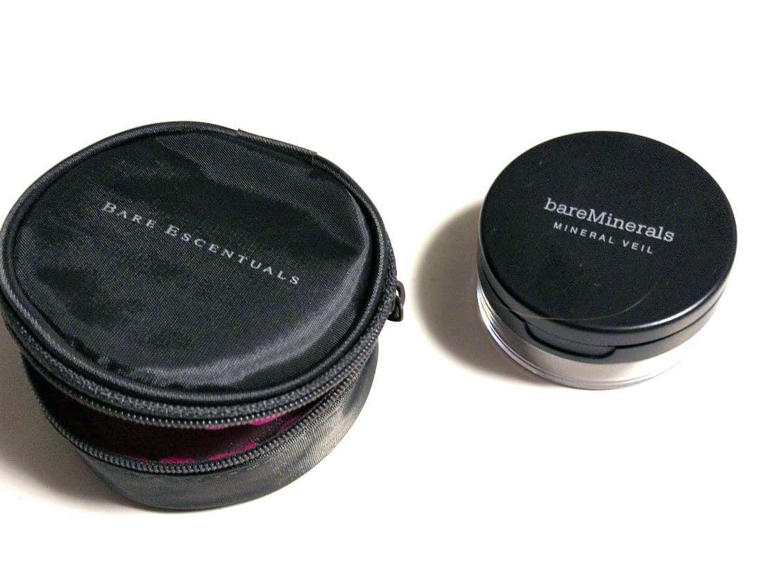 A black bareMinerals round foundation pouch with a zipper shown beside a bareMinerals foundation container on a white background.