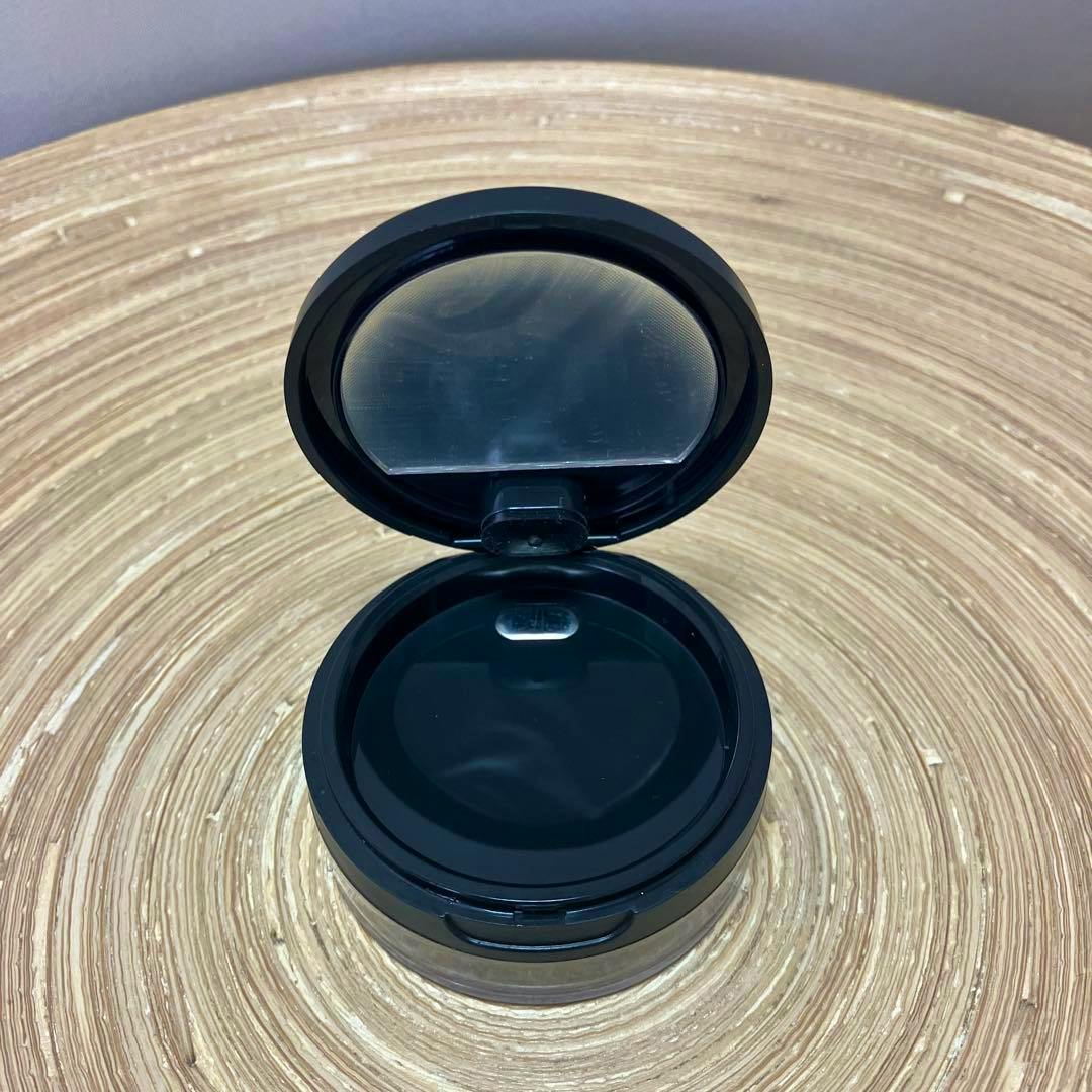 Open black plastic powder case for BareMinerals Mineral Veil shown open on a round woven surface.