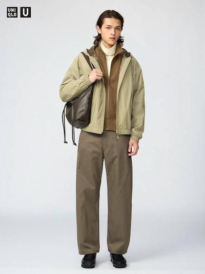 Front view of a male model wearing the men's barrel-leg chinos paired with a jacket and carrying a backpack.
