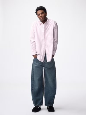 Male model wearing barrel-leg men's jeans shown full-length against a white background.