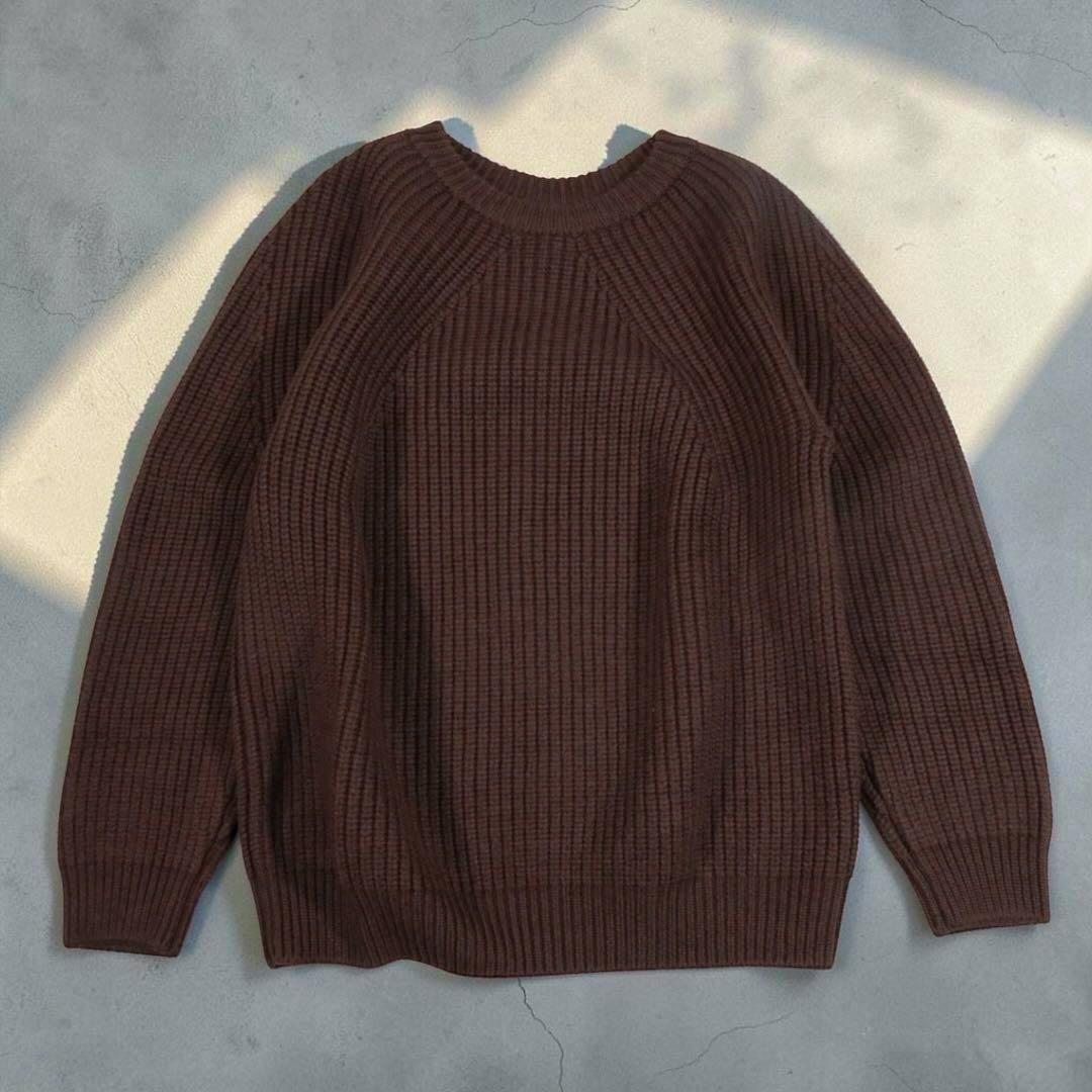 Brown ribbed wool sweater laid flat on a light background.