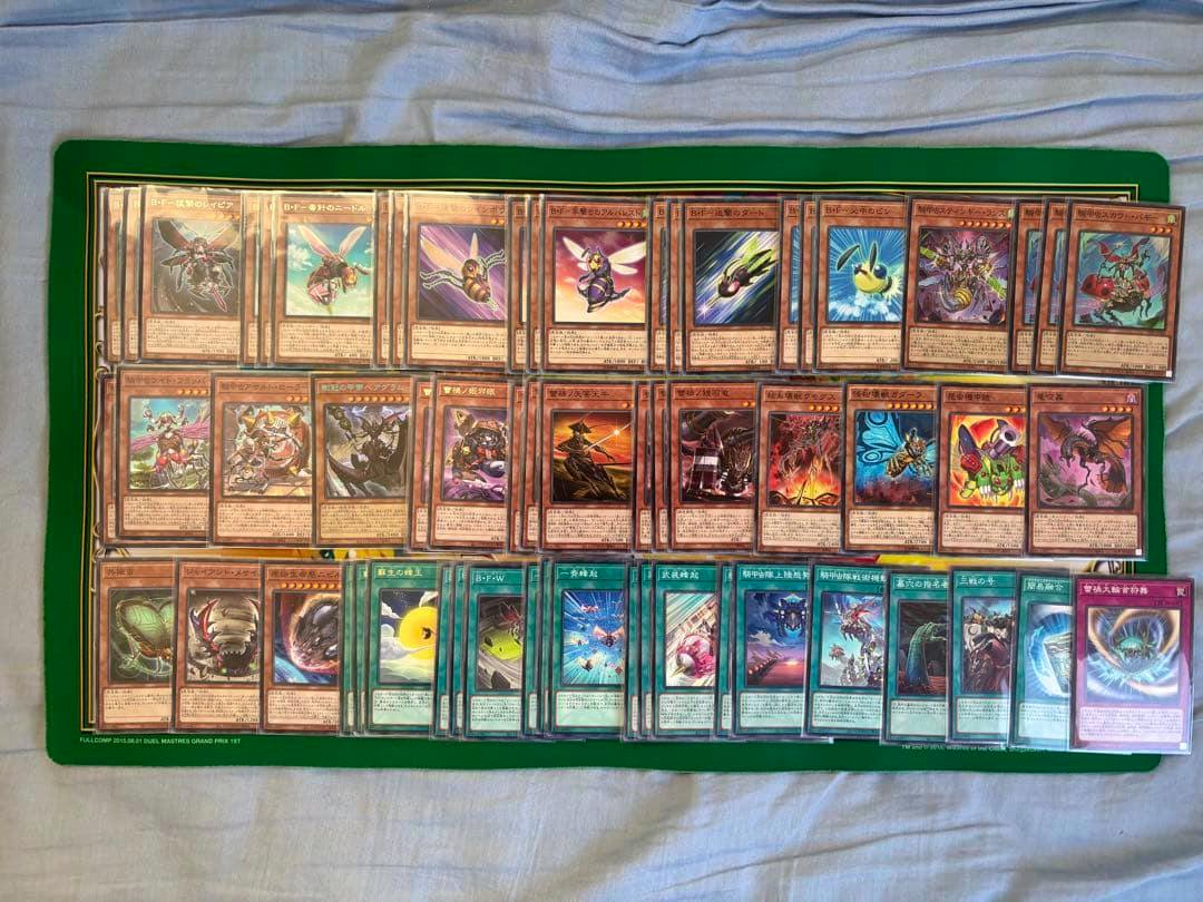 Photograph of many trading cards arranged in rows on a green playmat, showing multiple monster and spell cards from the deck.