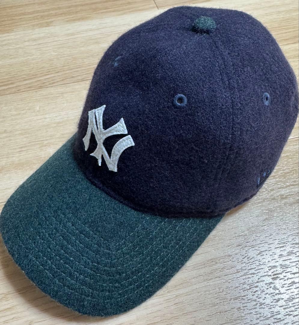 BEAMS/New Era 9TWENTY wool hat with an NY logo, dark navy crown and green brim photographed on a wooden surface.
