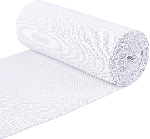 A roll of white woven flat elastic belt material with a portion unrolled on a surface.