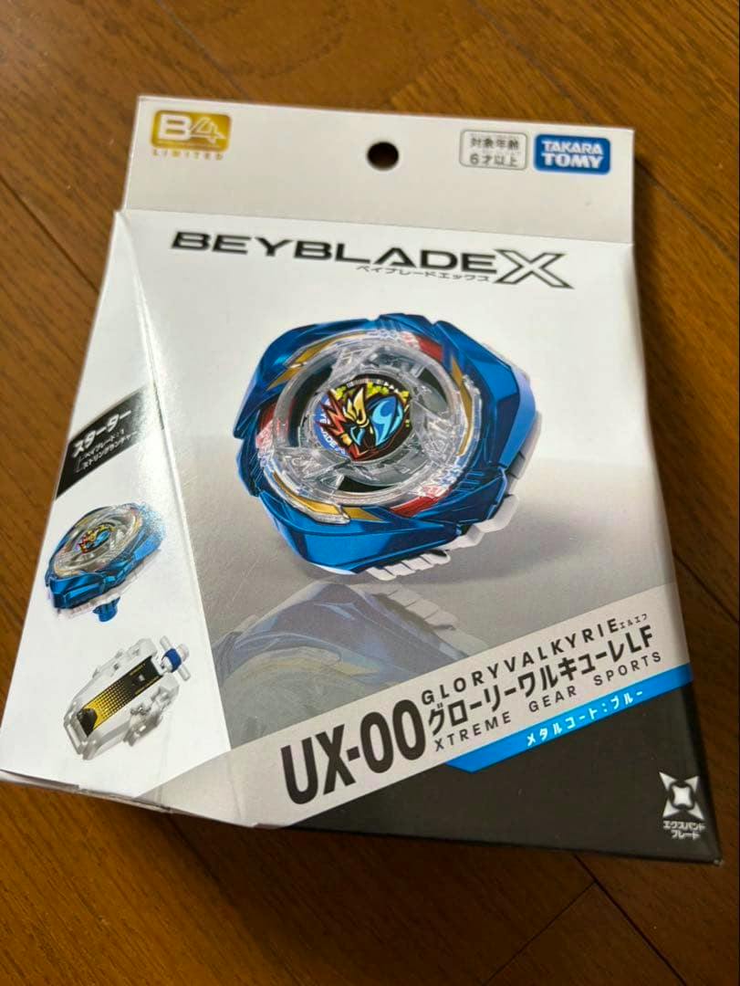 Photograph of the boxed Beyblade UX-00 Glory Valkyrie LF metal coat blue toy packaging on a wooden surface.