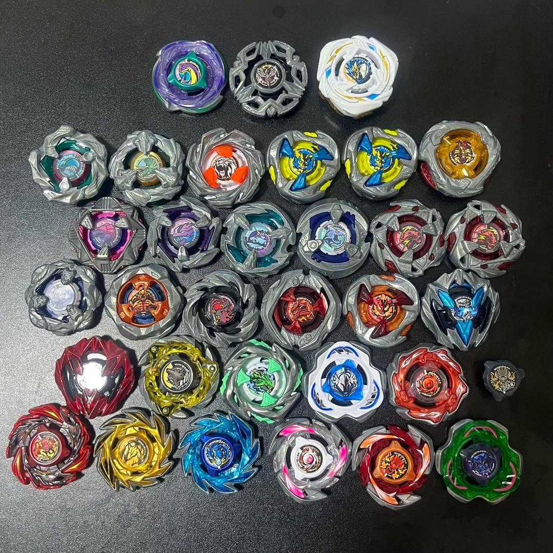 Multiple Beyblade X tops and plastic/metal layers arranged together on a black surface.