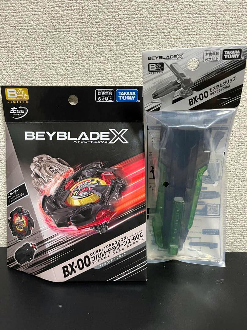 Unopened BEYBLADE X BX-00 Cobalt Dragoon boxed starter on the left and a sealed BX-00 custom grip in clear plastic packaging on the right.