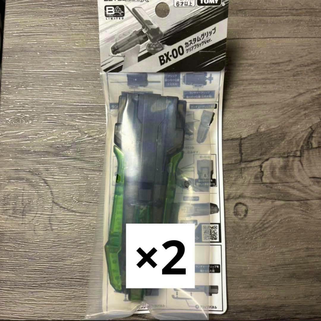 Packaged Beyblade BX-00 custom grip (clear black) in blister pack with a “×2” quantity label.