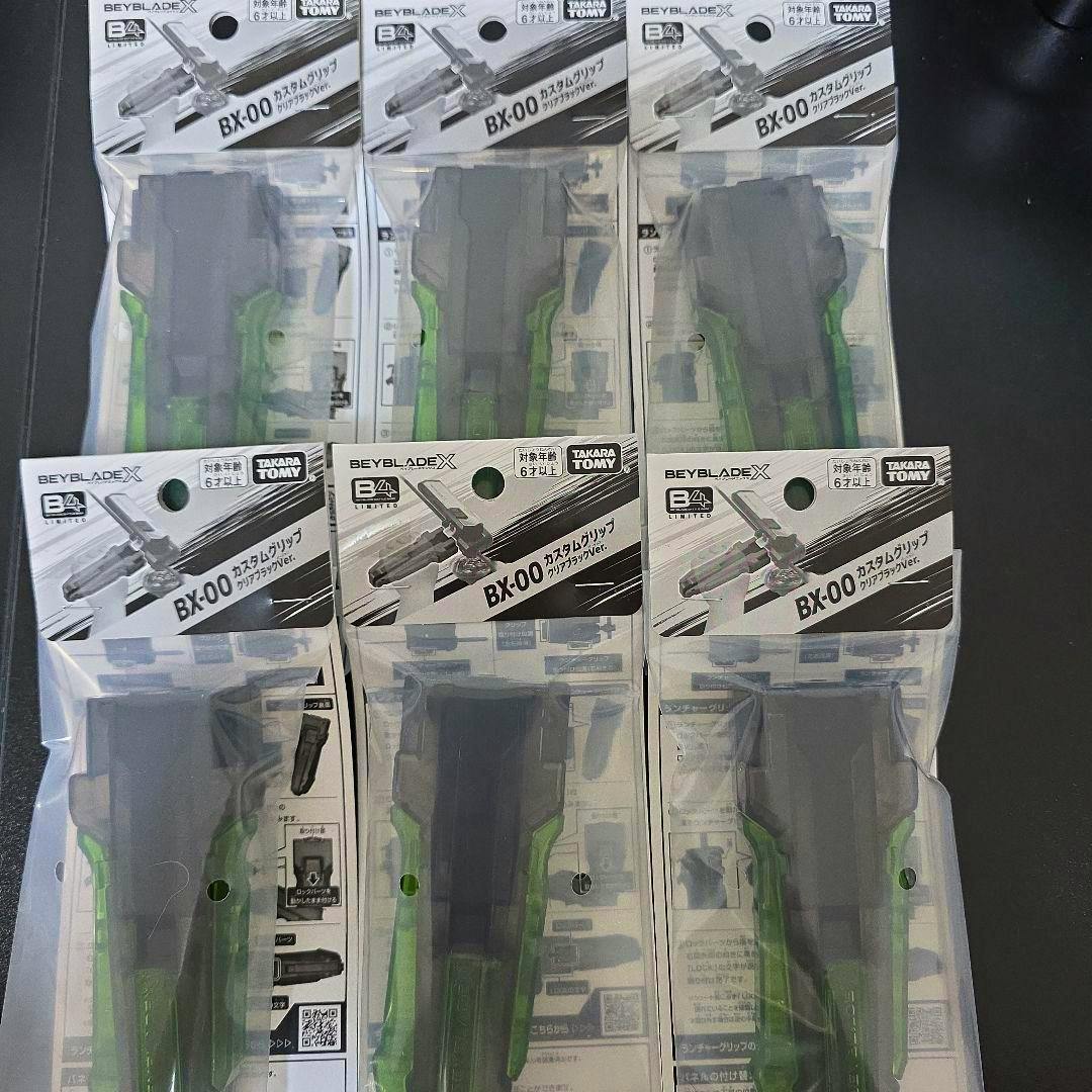 Six sealed BX-00 custom grip packages for Beyblade X arranged on a dark surface.