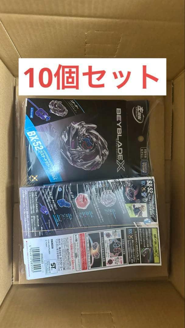 Top-down photo of a cardboard box containing a shrink-wrapped BX-52 Beyblade X starter package with a visible "10個セット" banner.