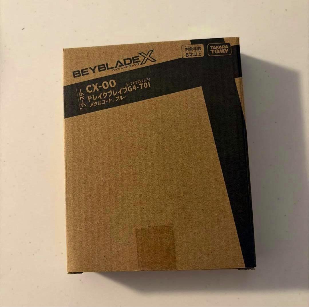 A cardboard Beyblade X product box labeled CX-00 ドレイクブレイブG4-70I with the Takara Tomy logo.