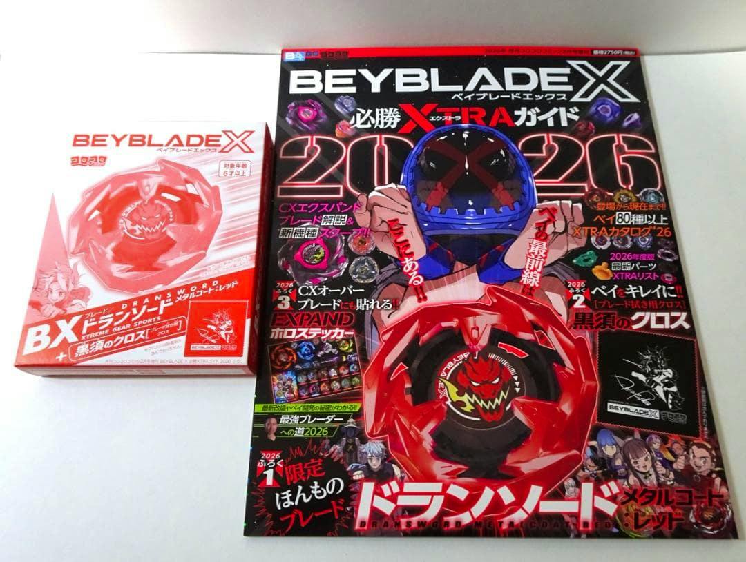 Front cover of the BEYBLADE X 必勝XTRAガイド 2026 magazine showing red Dransword artwork, with the boxed red Dransword placed to the left.