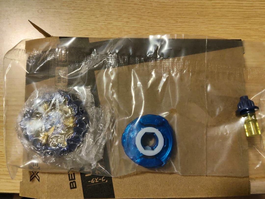 Beyblade X ナイトメイル plastic parts (top layer, disc, driver) shown in clear plastic bags on cardboard.
