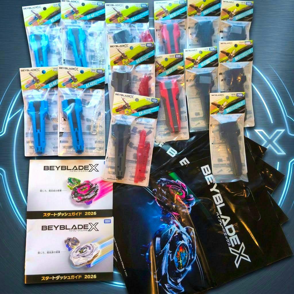 Multiple packaged Beyblade X launcher grips arranged with BeybladeX booklets and branded bags on a display surface.