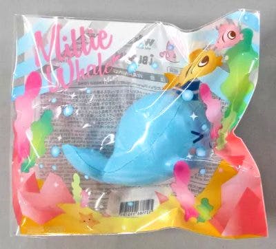 Light-blue whale squishy mascot toy visible inside clear colorful plastic packaging.
