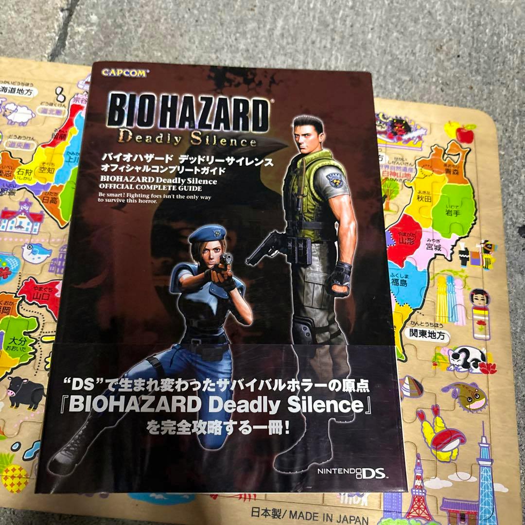 Front cover of the BIOHAZARD Deadly Silence official complete guide book showing the cover art and title.