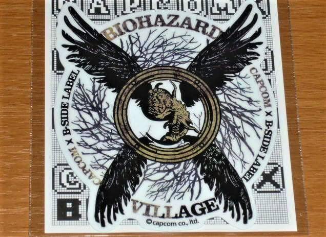 Clear photo of the Biohazard (Resident Evil) Village talisman logo sticker by B-SIDE LABEL/Capcom on a wooden surface.