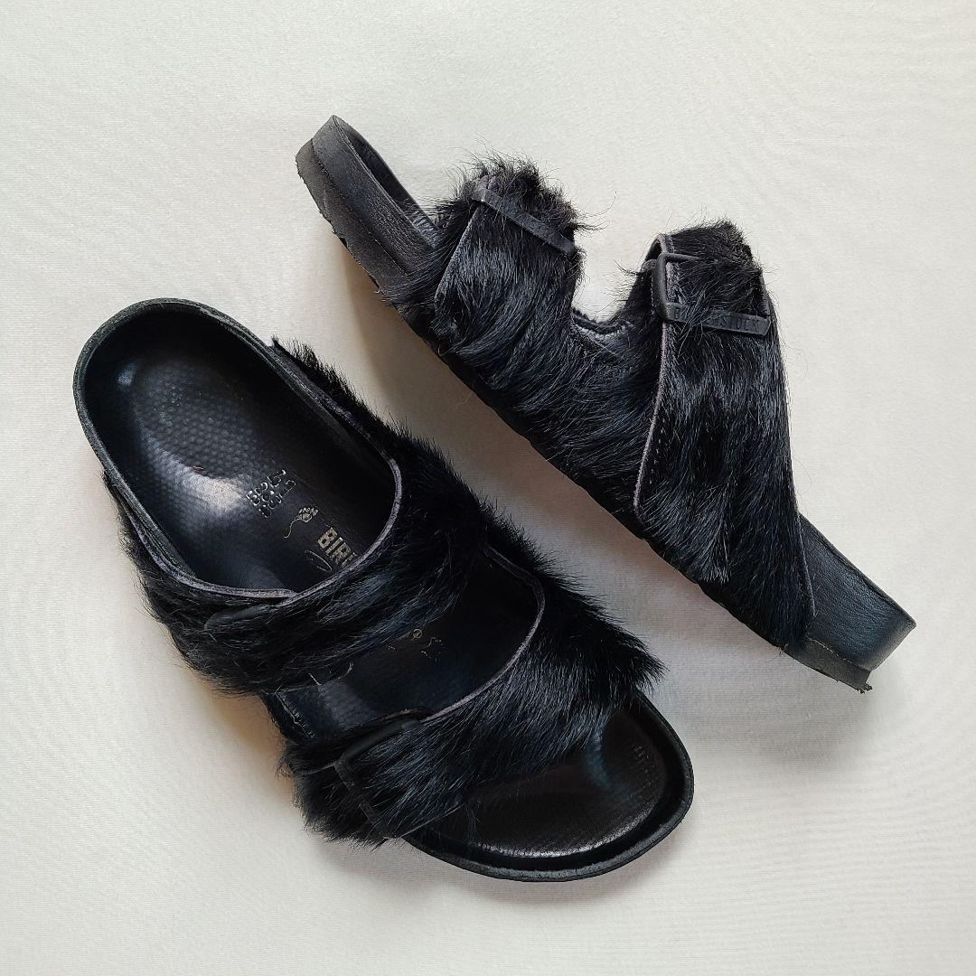 Top-down photo of black BIRKENSTOCK Rick Owens Arizona sandals with black hair-on (harako) fur straps on a white background.