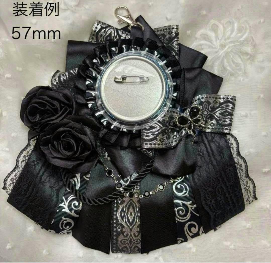 Black and silver fabric rosette with decorative roses and a 57mm can badge attached showing its pin back.
