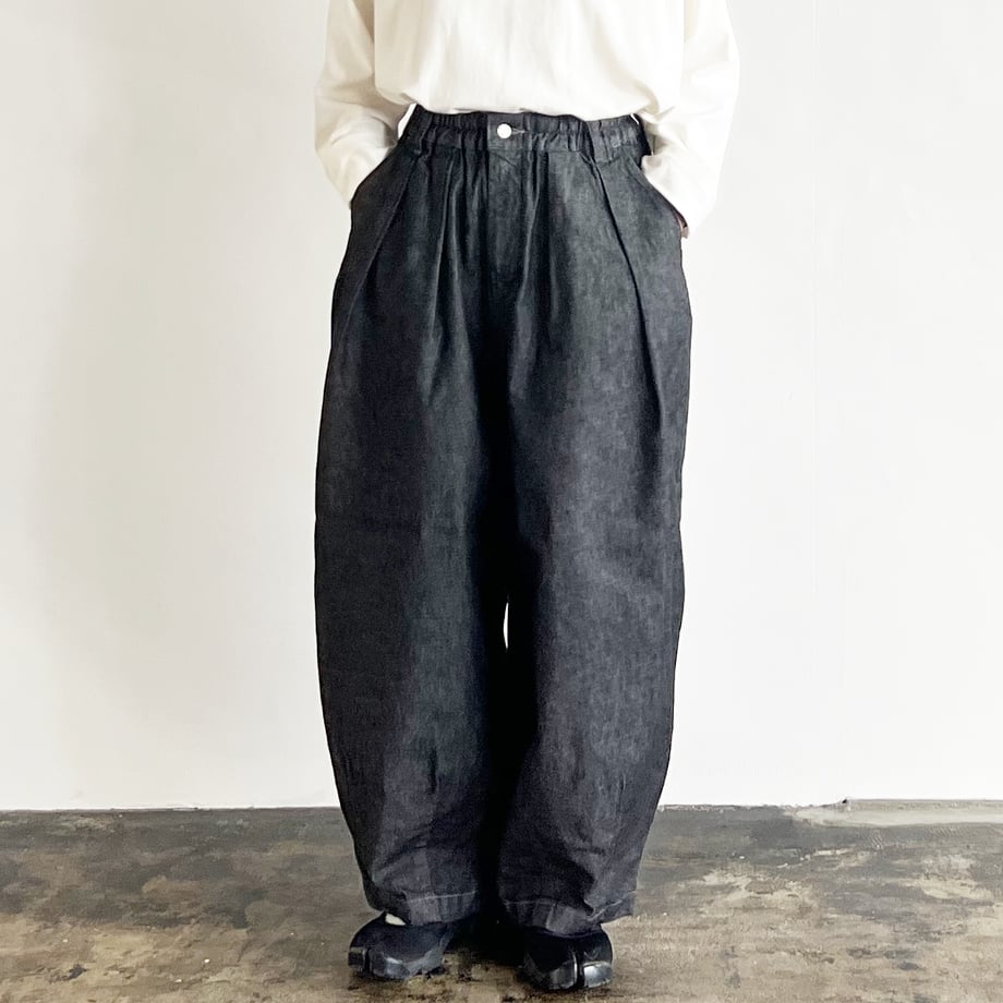 A model wearing the black denim circus pants showing the full-length baggy silhouette, elastic waist, and front pleats.