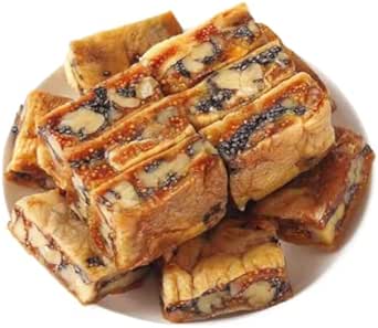 Close-up of stacked rectangular pieces of dried fig and walnut snack showing walnut pieces and black sesame seeds.