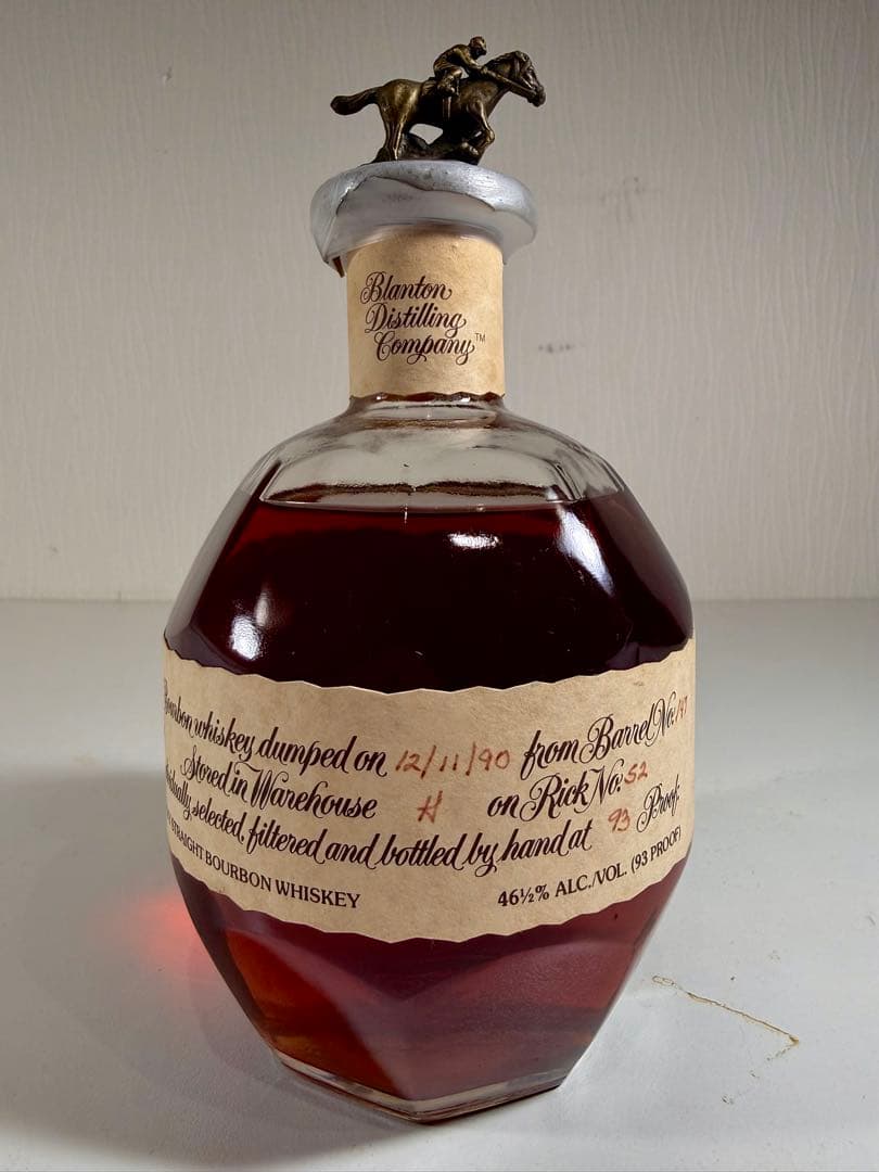 A Blanton's Single whiskey bottle with a horse-and-jockey stopper and a paper label showing a handwritten dump date.