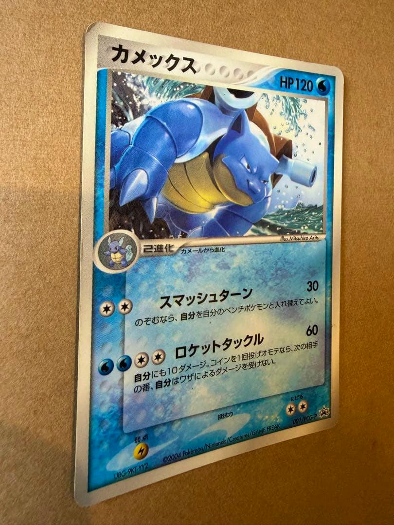 Photograph of the カメックス プロモ 001/PCG-P trading card showing the full card artwork and Japanese text.