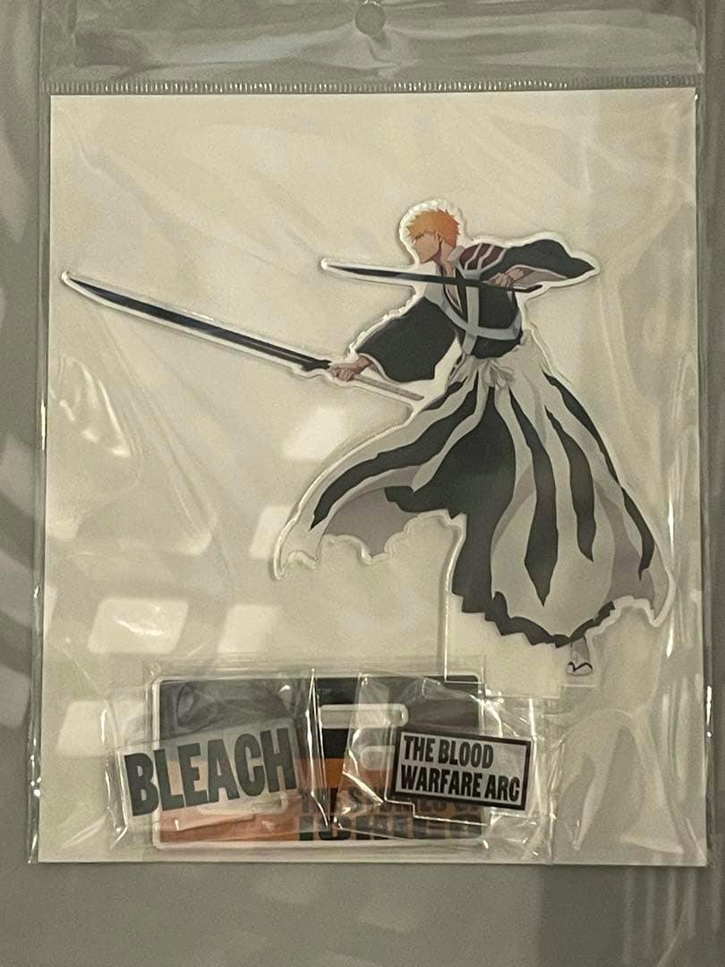Packaged acrylic decorative stand of Ichigo from BLEACH showing him holding a sword, with separate printed base pieces labeled "BLEACH" and "THE BLOOD WARFARE ARC" visible.