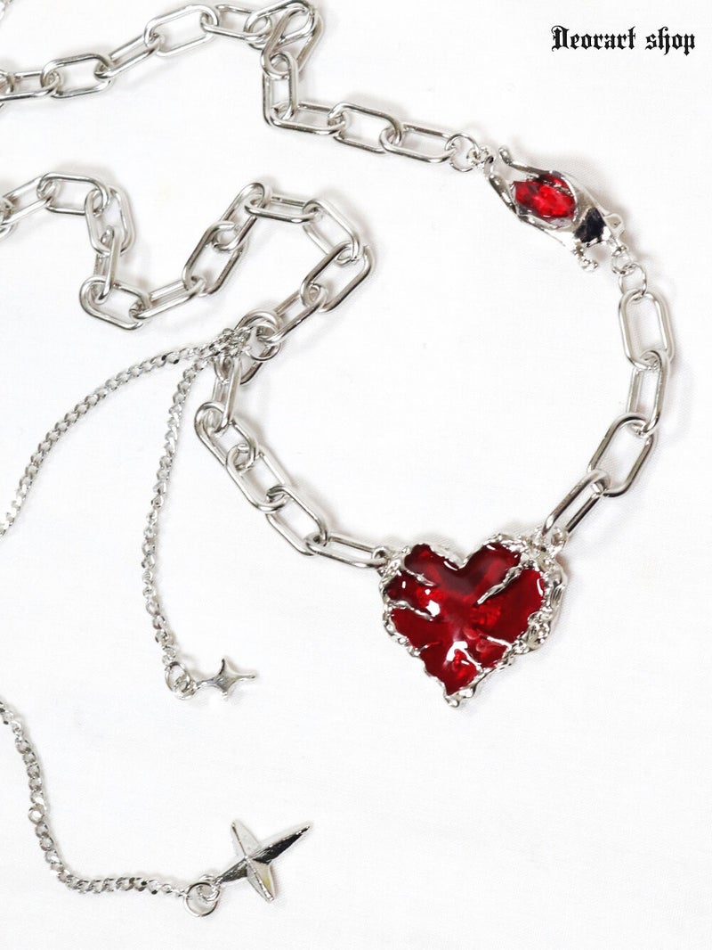Non-precious metal gothic chain choker necklace with a red heart pendant and a small cross charm on a white background.