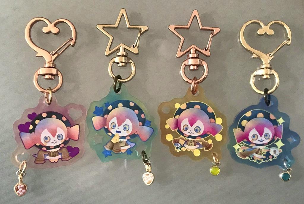 Four acrylic keychains with character artwork and heart/star metal clasps shown front-facing on a neutral background.