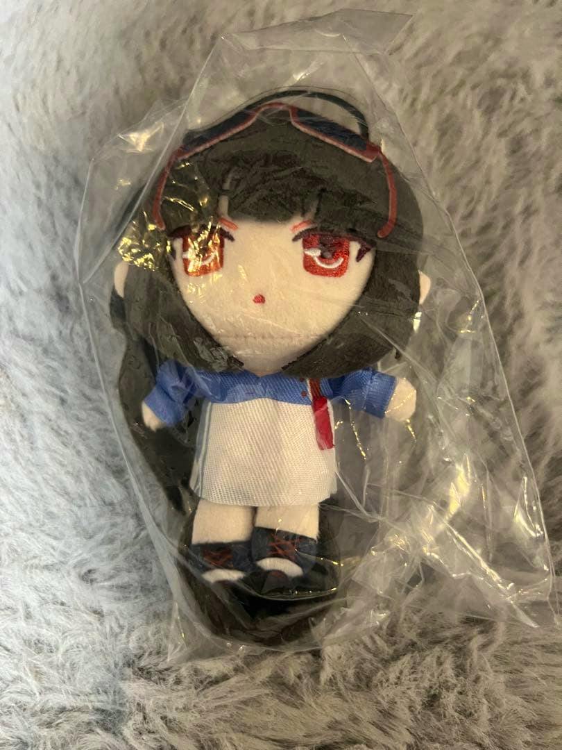 Front view of the 【中国限定】ブルーアーカイブ ライブ限定 ぬいぐるみ 調月リオ plush toy inside a clear plastic bag on a fuzzy surface.
