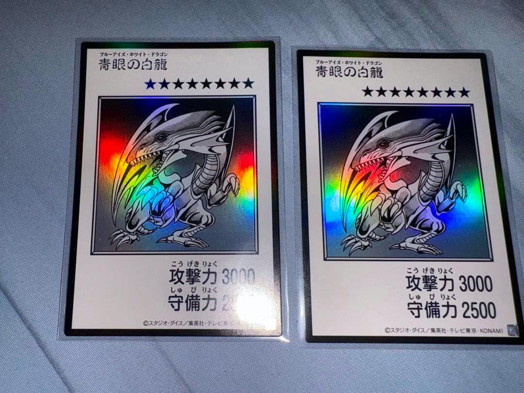 Two monochrome Blue‑Eyes White Dragon trading cards shown front side with holographic foil and Japanese text.