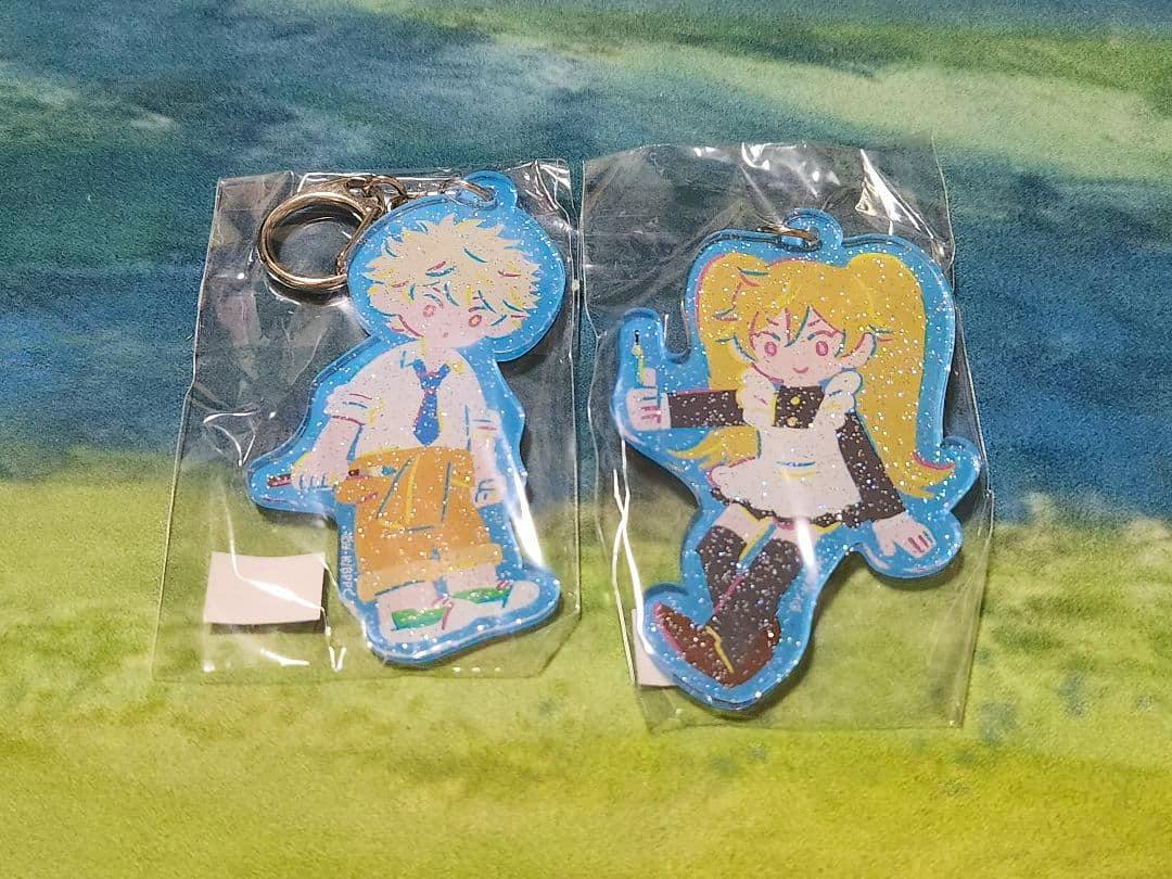 Two glitter acrylic Blue Period keychain charms in plastic packaging showing the front artwork.