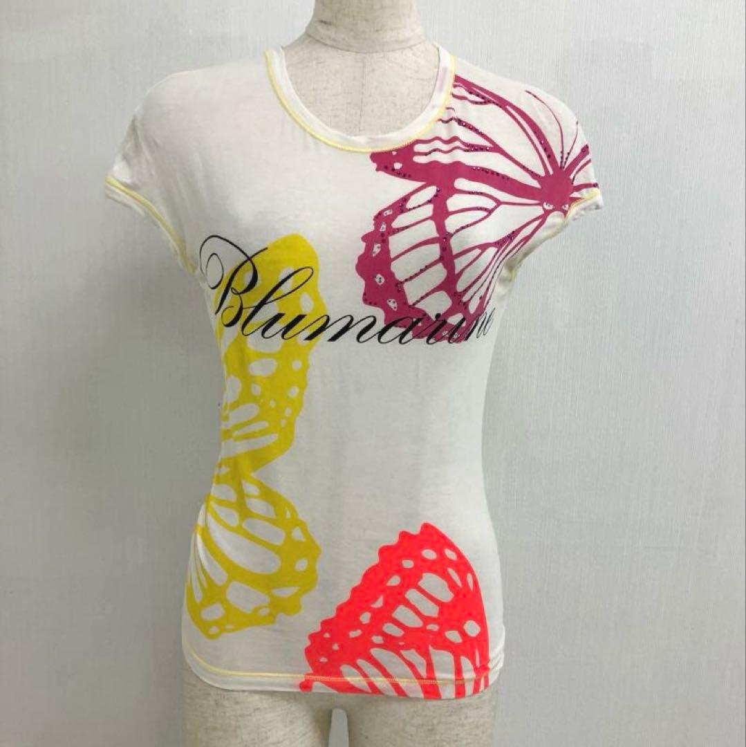 White women's cotton T-shirt with large pink, yellow, and red butterfly prints and script logo displayed on a mannequin.