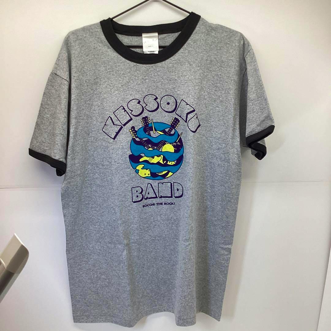 Front view of a gray ringer T-shirt with dark collar and sleeve trim and a colorful graphic reading “KESSOKU BAND” on the chest.