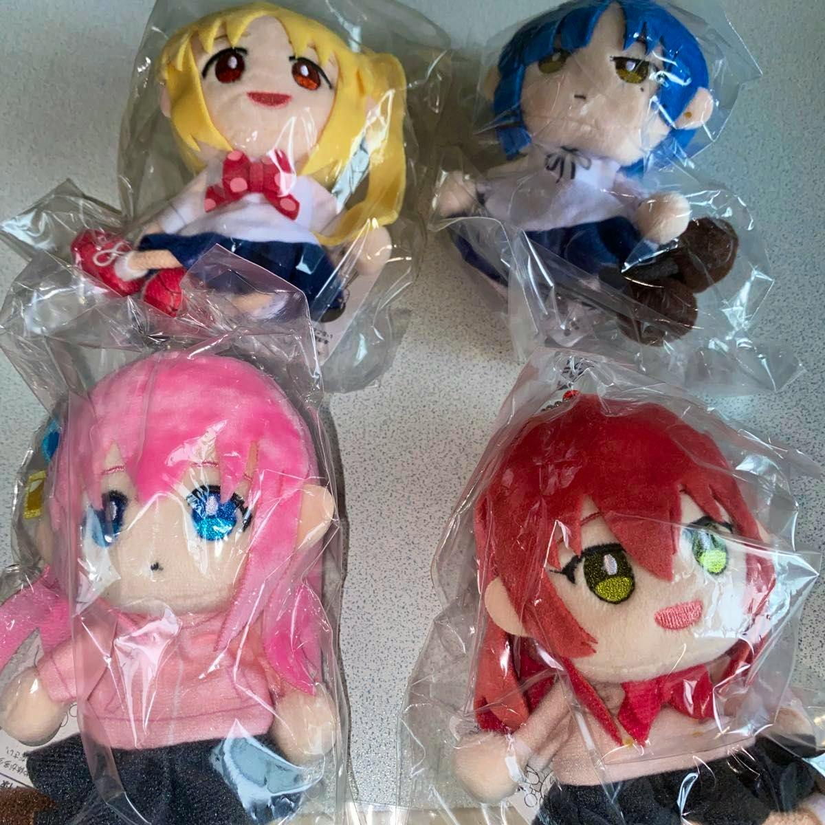Four puppet charm plush toys from the set are visible, each packaged in clear plastic and arranged in a 2-by-2 layout.