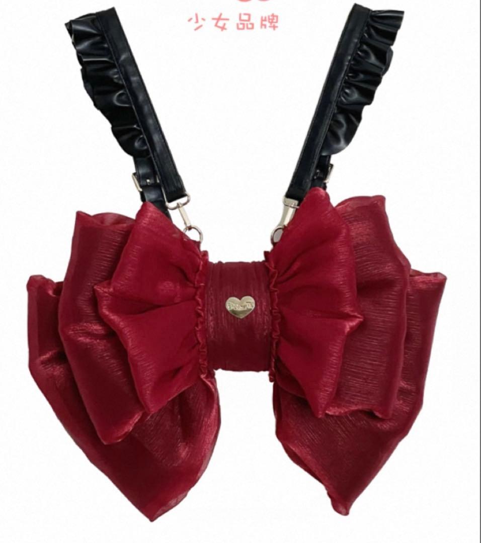 Red organza ribbon waist bag with black ruffled straps and a small gold heart emblem, shown on a white background.