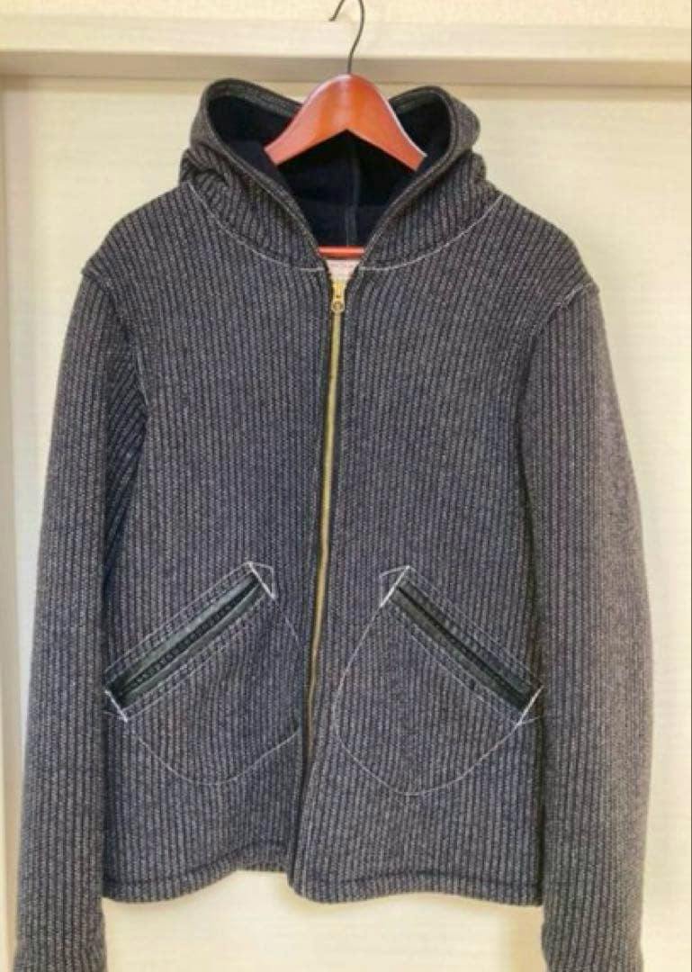 Front view of a men's wool BONCOURA hooded jacket with a center zipper and two front pockets hanging on a hanger.