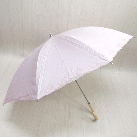 Opened pink Borsalino long umbrella with lace trim displayed on a light floor.