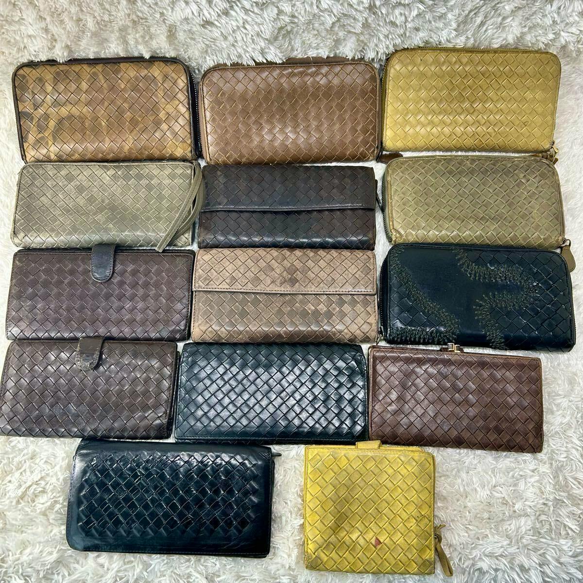 Fourteen Bottega Veneta intrecciato wallets in various colors laid out on a light fabric surface.