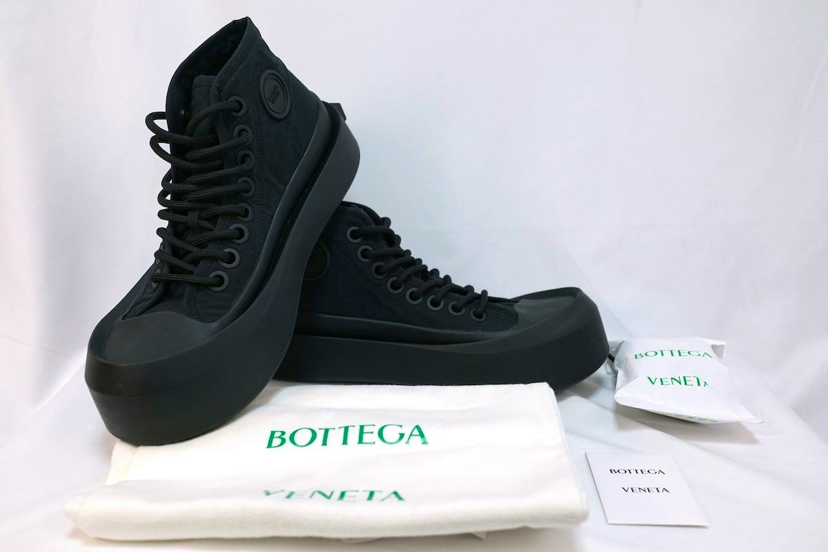 Pair of black Bottega Veneta jumbo sneakers displayed on a white background with branded dust bag and tags.