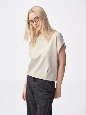 Model wearing the sleeveless bottle-neck women's shirt shown from mid-thigh up.