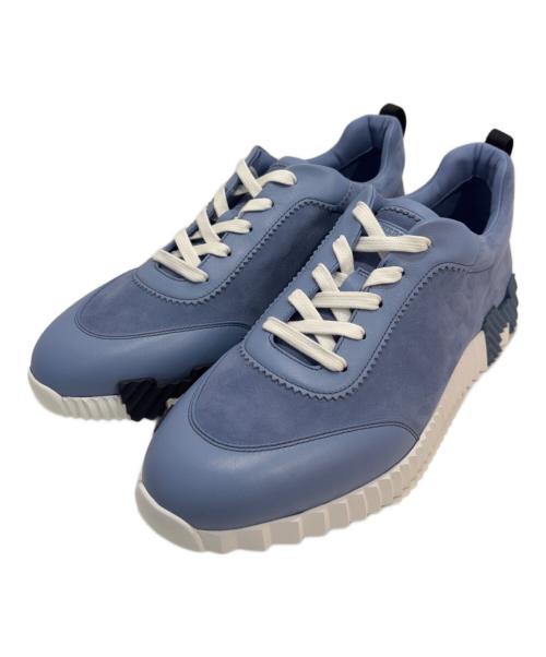 Pair of blue textile sneakers with white laces and chunky white soles on a white background.