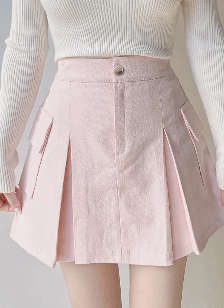 Front view of a pink box-pleated A-line mini skirt with faux cargo pockets worn by a model.